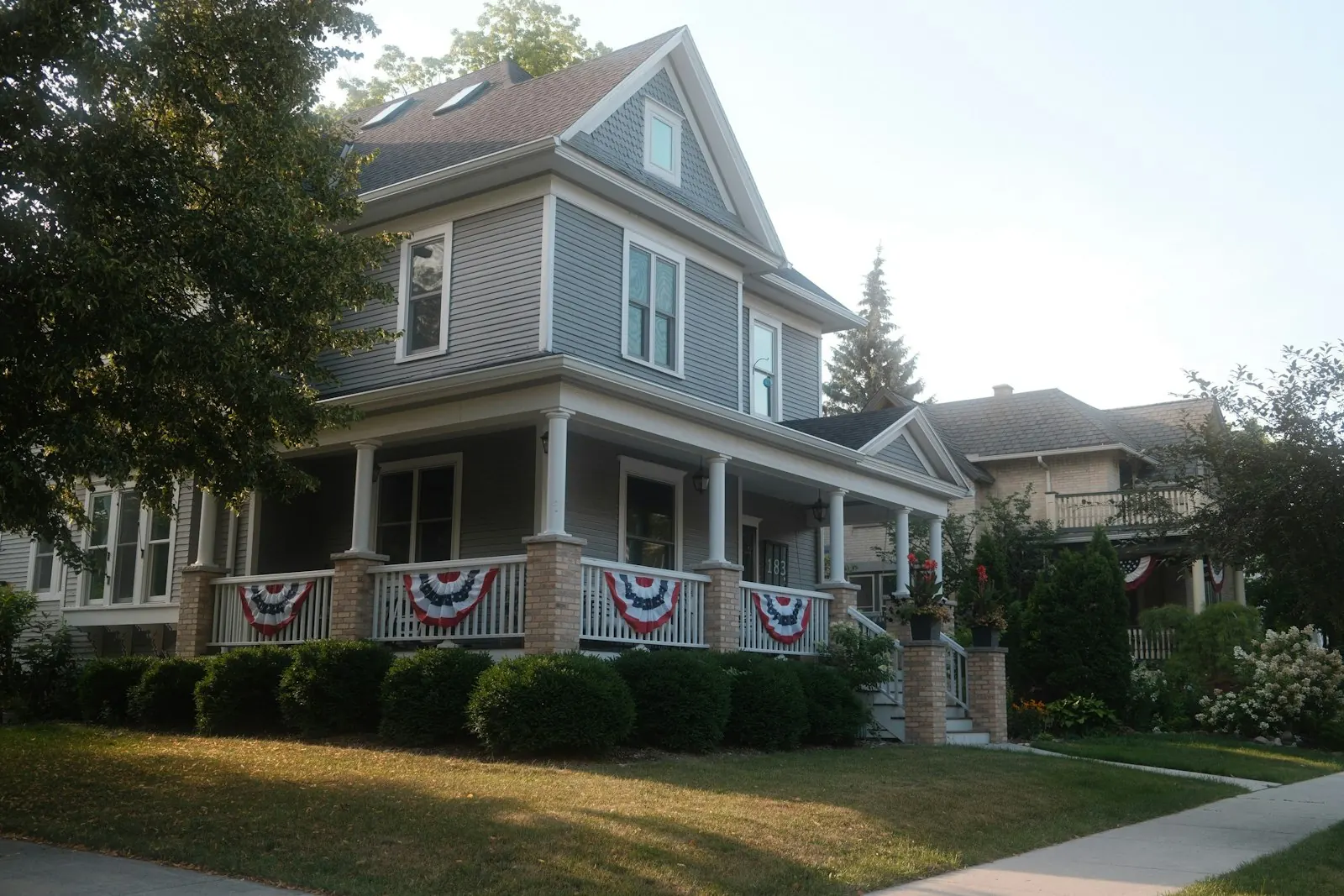 A two story house with a front porch decorated with patriotic bunting