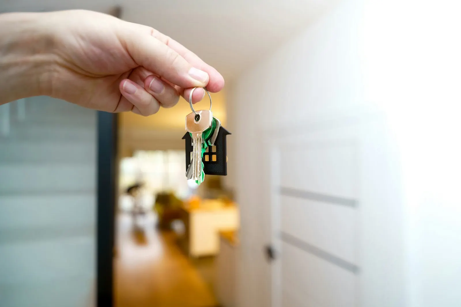 Keys with a house shaped tag being held out at a front door